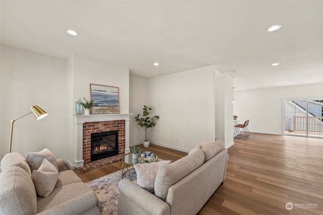 living room featuring wood-type flooring and a brick fireplace