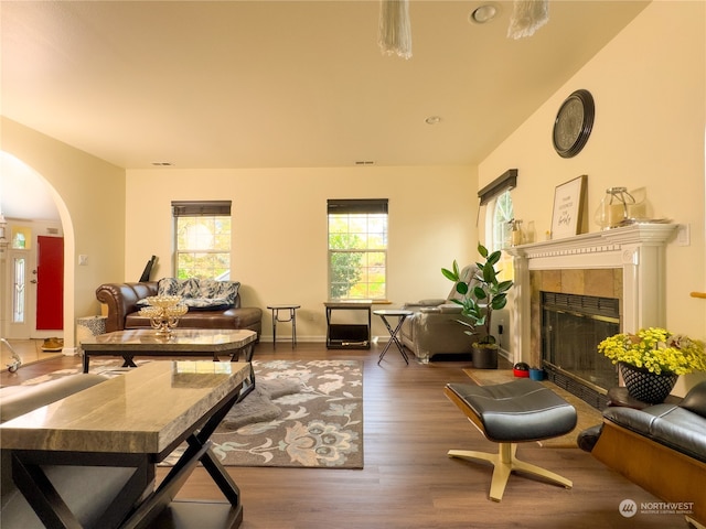 living room with a tiled fireplace and dark hardwood / wood-style flooring