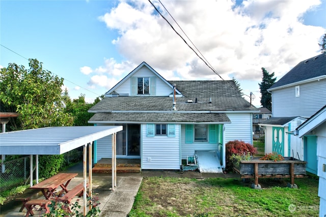 rear view of house featuring a carport and a yard