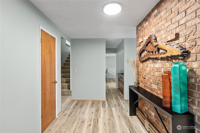 hallway with a textured ceiling and light hardwood / wood-style floors