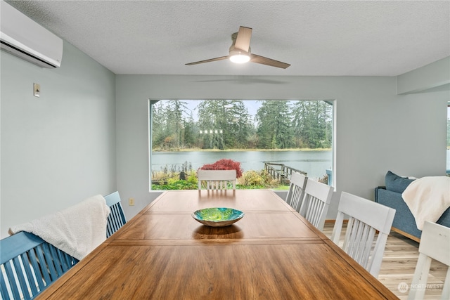 dining room with a wall mounted AC, hardwood / wood-style flooring, a water view, and a wealth of natural light