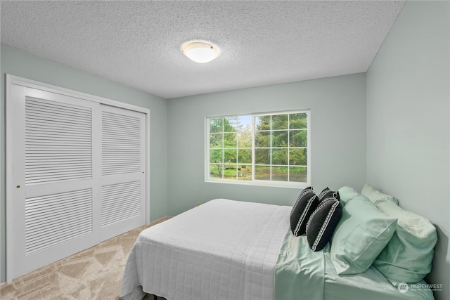 carpeted bedroom with a closet and a textured ceiling