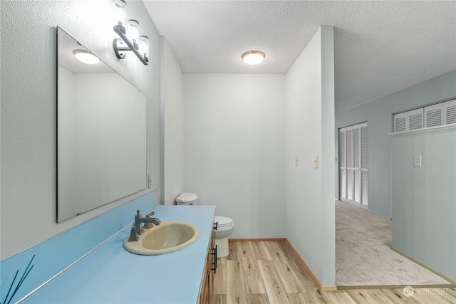 bathroom featuring vanity, a textured ceiling, wood-type flooring, and toilet