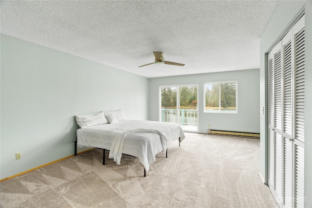 carpeted bedroom with a baseboard heating unit, a textured ceiling, and ceiling fan