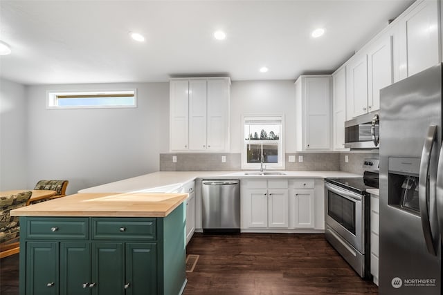 kitchen with a wealth of natural light, dark wood-type flooring, appliances with stainless steel finishes, and white cabinets