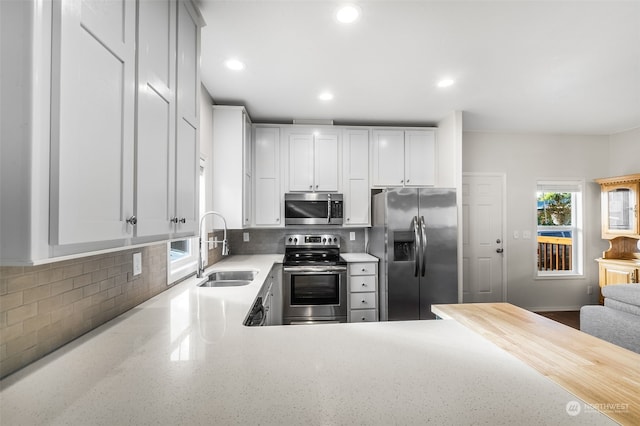 kitchen with stainless steel appliances, decorative backsplash, sink, and plenty of natural light