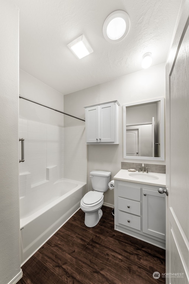 full bathroom with hardwood / wood-style floors, a textured ceiling, toilet, vanity, and bathing tub / shower combination