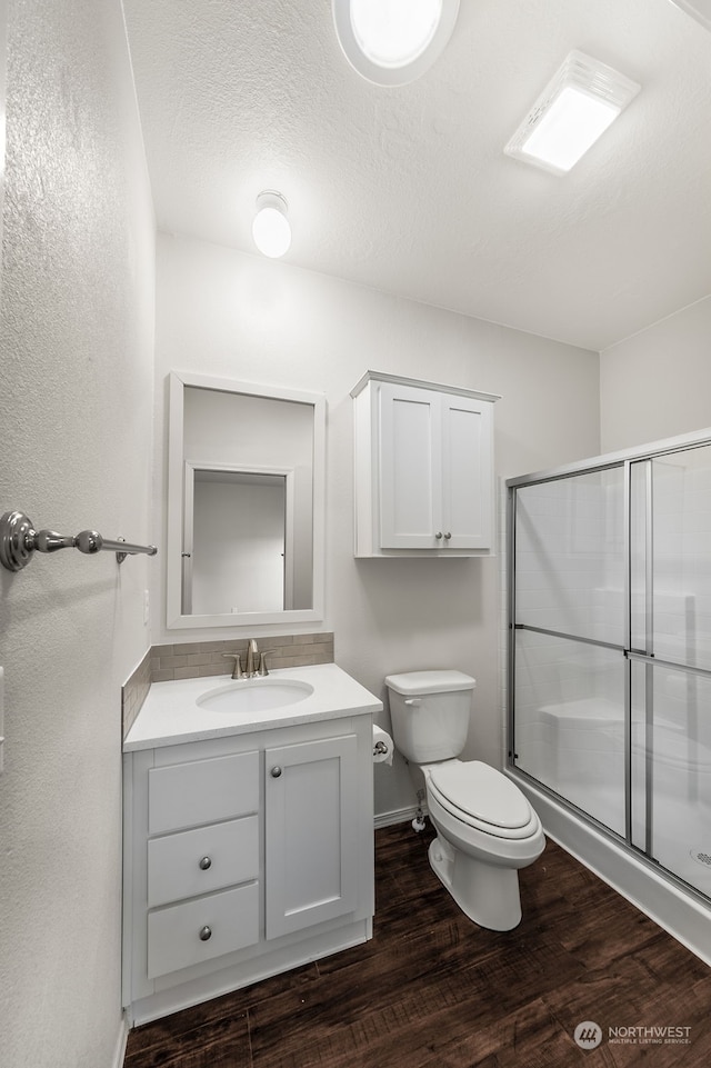 bathroom featuring a textured ceiling, toilet, walk in shower, vanity, and hardwood / wood-style flooring