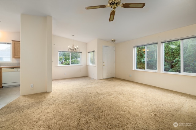 unfurnished living room featuring a wealth of natural light, vaulted ceiling, light colored carpet, and ceiling fan with notable chandelier