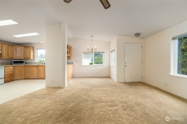 unfurnished living room with a chandelier, vaulted ceiling, and light colored carpet