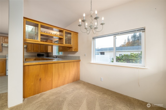 kitchen featuring kitchen peninsula, an inviting chandelier, decorative light fixtures, light colored carpet, and vaulted ceiling