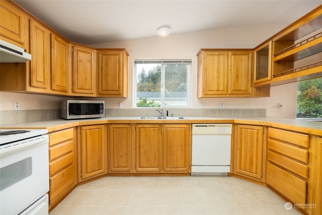 kitchen with sink, white appliances, and vaulted ceiling