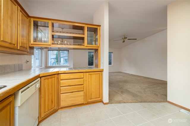 kitchen featuring tile countertops, light colored carpet, ceiling fan, and dishwasher