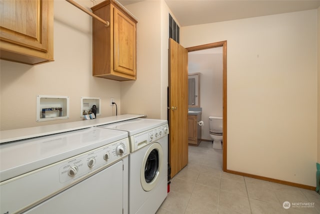 clothes washing area with light tile patterned floors, cabinets, and washer and dryer