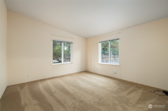 carpeted spare room with lofted ceiling