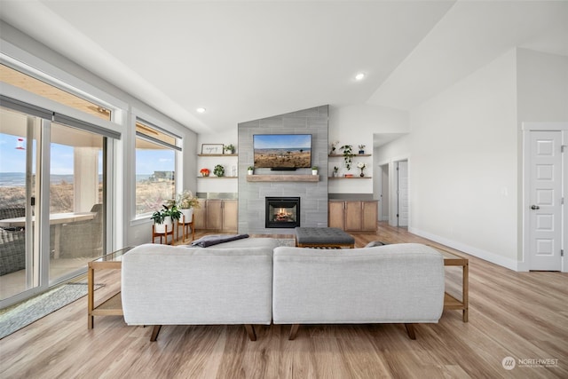 living room featuring light hardwood / wood-style floors, lofted ceiling, and a tile fireplace