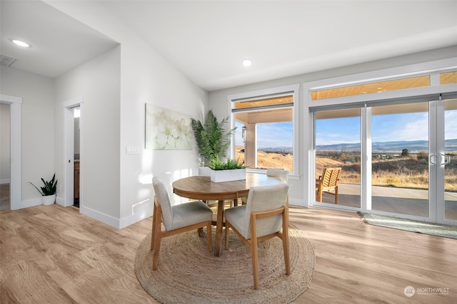 dining space featuring vaulted ceiling and light hardwood / wood-style flooring