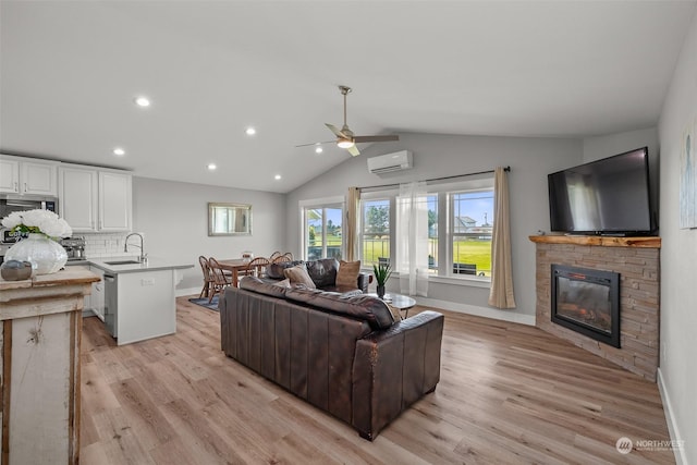 living area with an AC wall unit, light wood finished floors, baseboards, and a stone fireplace