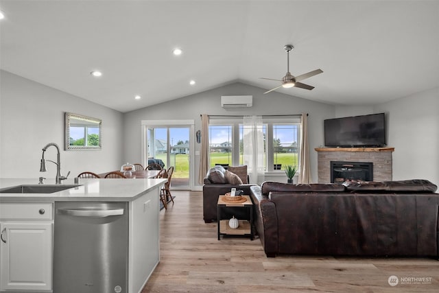 interior space featuring stainless steel dishwasher, light wood-type flooring, a sink, lofted ceiling, and open floor plan