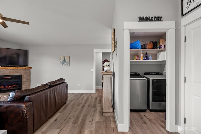 living area with light wood-type flooring, ceiling fan, washing machine and dryer, and a fireplace