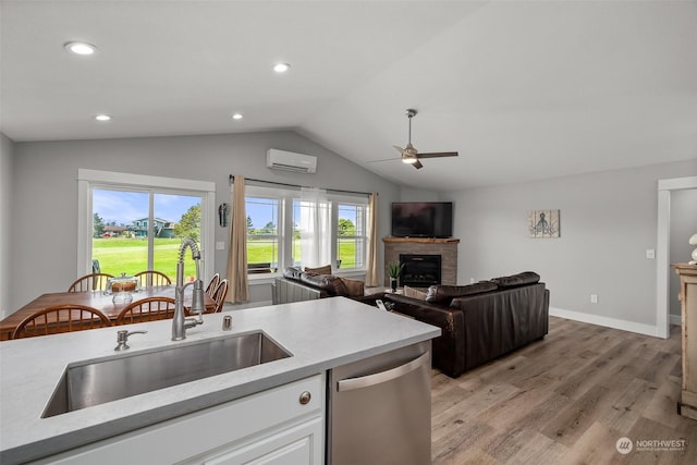 kitchen featuring ceiling fan, stainless steel dishwasher, a wall mounted air conditioner, a sink, and light wood finished floors