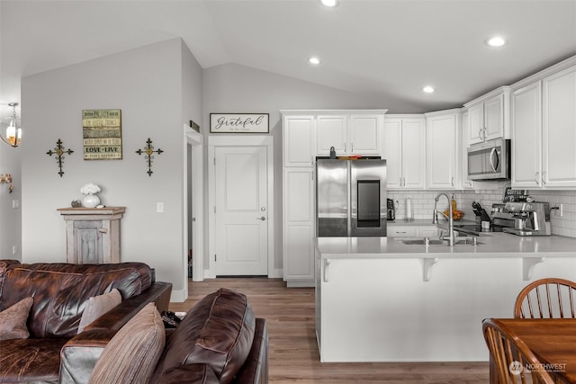 kitchen with a peninsula, open floor plan, appliances with stainless steel finishes, and a sink