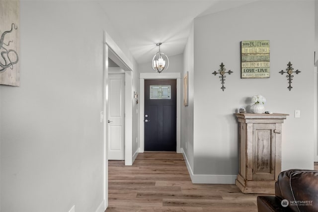 foyer featuring an inviting chandelier, baseboards, wood finished floors, and vaulted ceiling