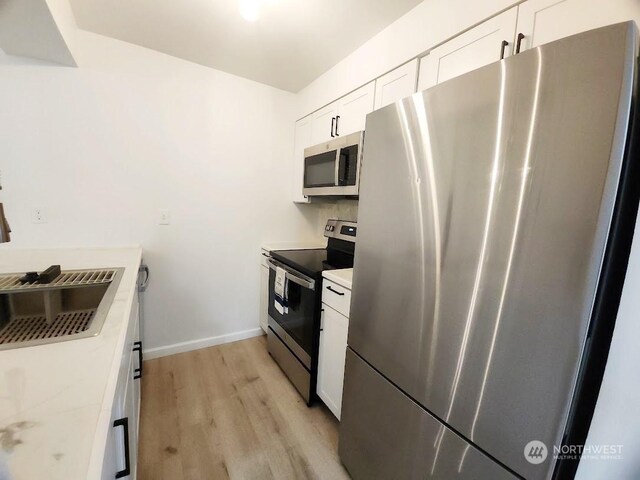 3600 Narrows View Ln Unit 201, Bremerton, WA 98310 - kitchen featuring stainless steel appliances, light wood finished floors, white cabinetry, light countertops, and baseboards