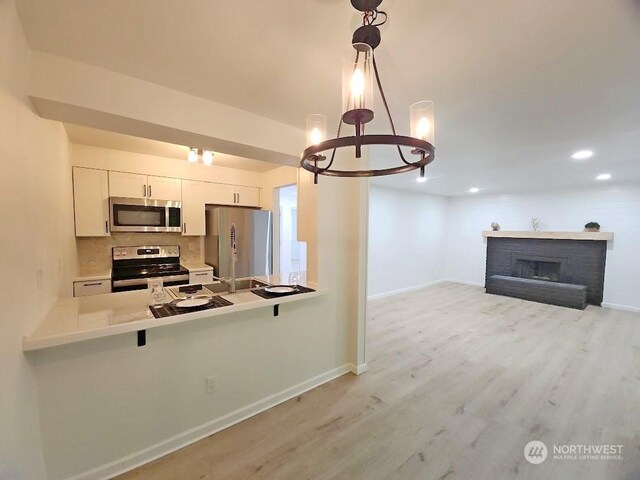 3600 Narrows View Ln Unit 201, Bremerton, WA 98310 - kitchen featuring appliances with stainless steel finishes, a peninsula, light wood-type flooring, white cabinetry, and a chandelier