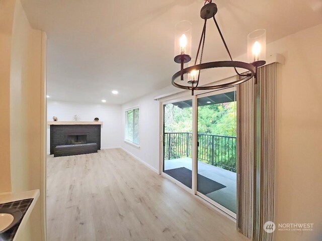 3600 Narrows View Ln Unit 201, Bremerton, WA 98310 - unfurnished living room with a chandelier, wood finished floors, a fireplace, and baseboards