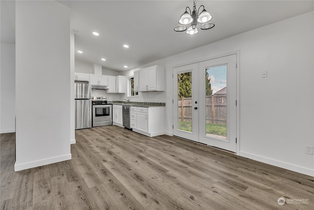 kitchen with appliances with stainless steel finishes, french doors, vaulted ceiling, pendant lighting, and white cabinets