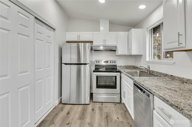 kitchen with white cabinets, stainless steel appliances, sink, and vaulted ceiling