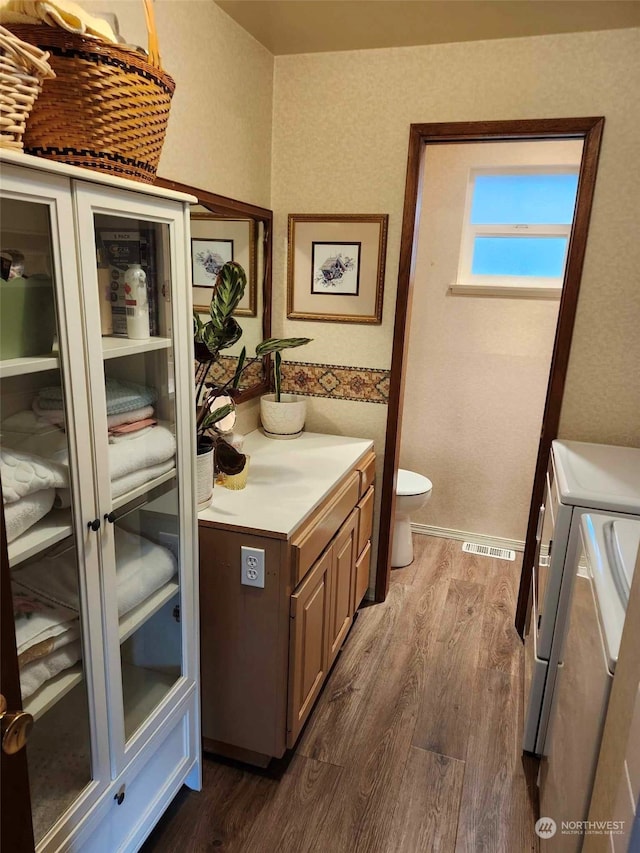 bathroom featuring hardwood / wood-style floors, separate washer and dryer, vanity, and toilet