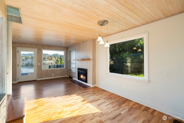 unfurnished living room with wood ceiling, wood-type flooring, and wooden walls