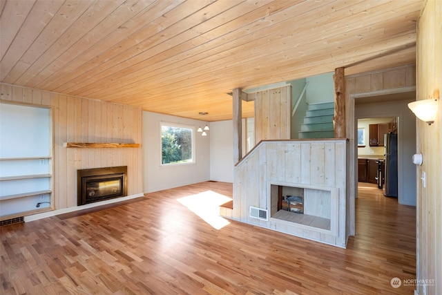 unfurnished living room with wood ceiling, hardwood / wood-style floors, lofted ceiling, built in shelves, and wooden walls