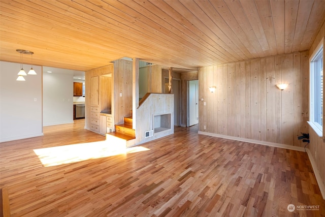 unfurnished living room featuring light hardwood / wood-style floors, wood ceiling, and wooden walls