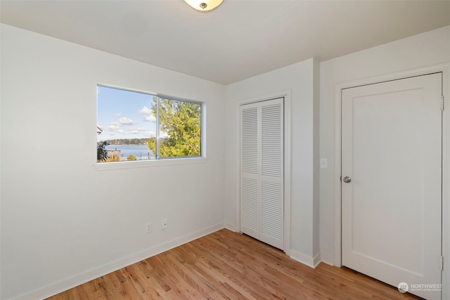 unfurnished bedroom with a closet and light wood-type flooring