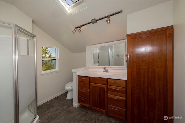 bathroom with vanity, vaulted ceiling with skylight, toilet, and walk in shower