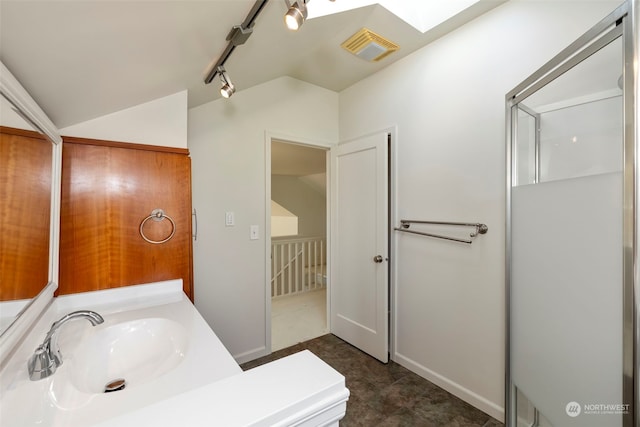 bathroom featuring vanity, a shower with shower door, track lighting, and a skylight