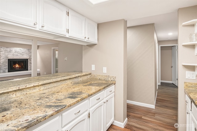 kitchen with white cabinets, light stone countertops, and hardwood / wood-style floors