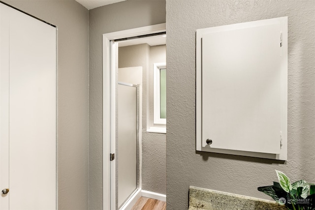 bathroom featuring a shower with door and wood-type flooring