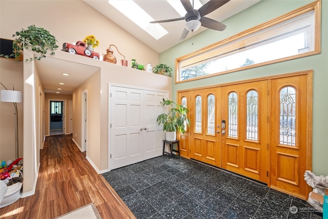 entryway with dark wood-type flooring, ceiling fan, high vaulted ceiling, and a skylight