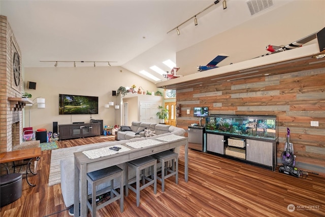 13629 Rector Rd, Bow, WA 98232 - living area with rail lighting, a brick fireplace, wood finished floors, vaulted ceiling, and wooden walls