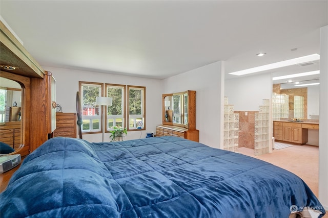 carpeted bedroom with ensuite bath and sink