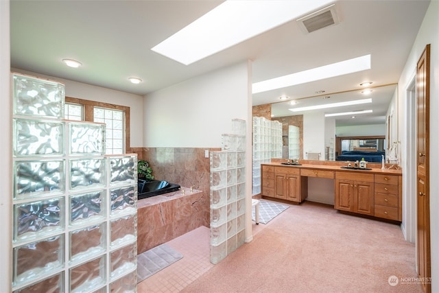 bathroom featuring vanity, tile walls, plus walk in shower, and a skylight