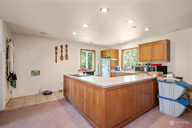 kitchen with kitchen peninsula, sink, white refrigerator, and light colored carpet