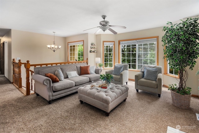 carpeted living room with ceiling fan with notable chandelier