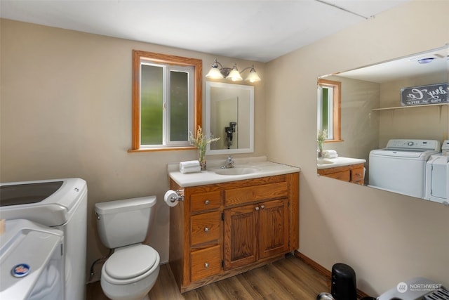 bathroom featuring toilet, independent washer and dryer, hardwood / wood-style floors, and vanity