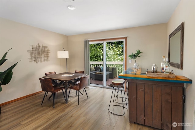 dining area with wood-type flooring and indoor bar