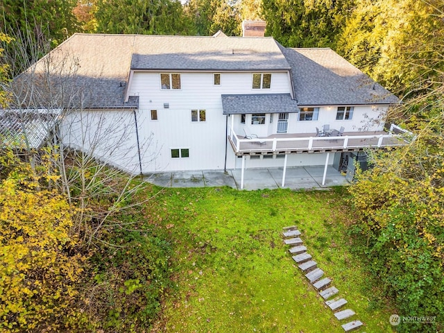 back of house with a yard, a patio, a chimney, and roof with shingles